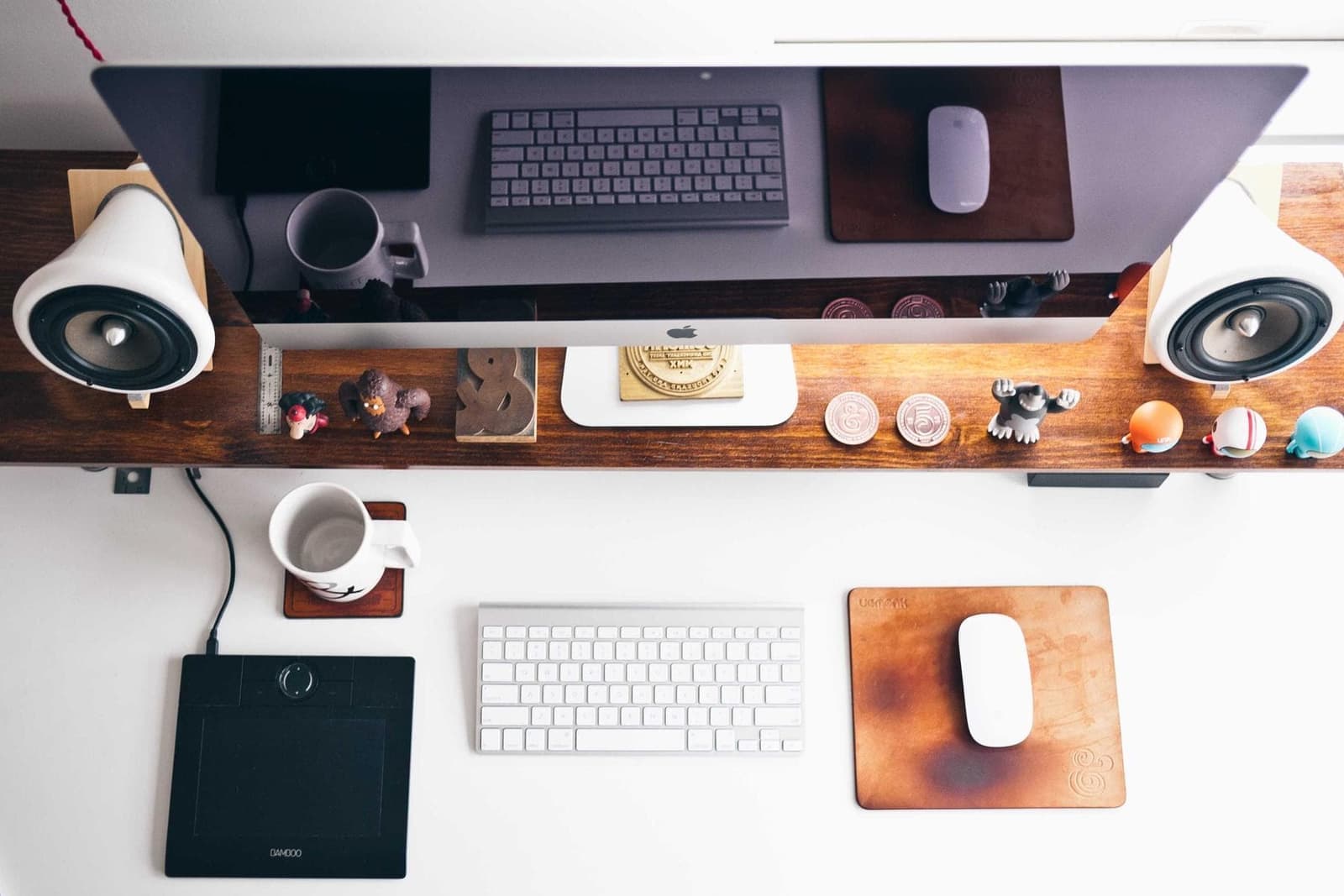 A tidy desk seen from above, with a monitor, keyboard and speakers.