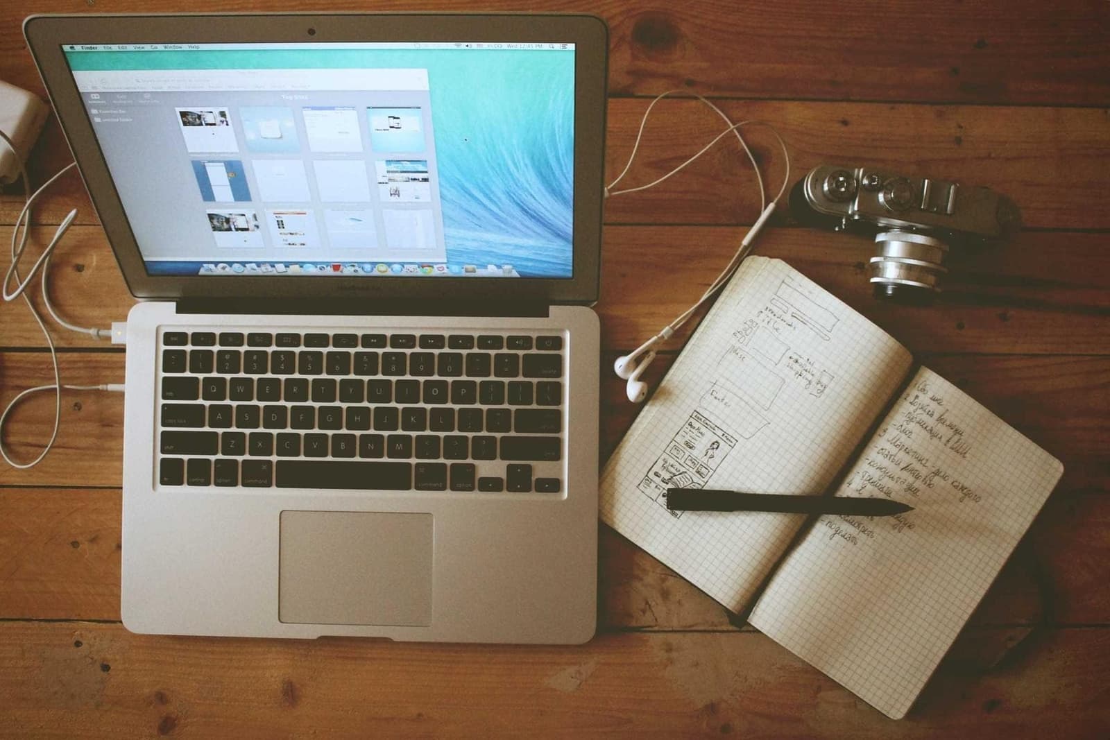 An open laptop beside a notebook and pen.
