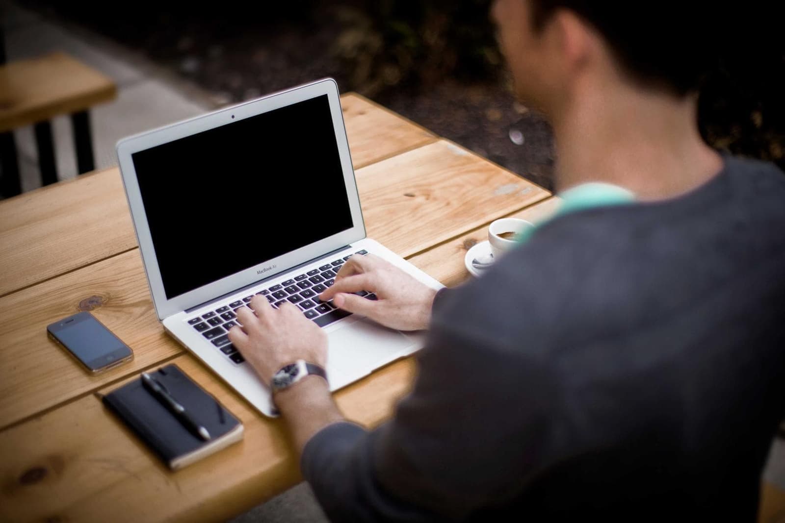 Hands typing on a laptop at a wooden table.
