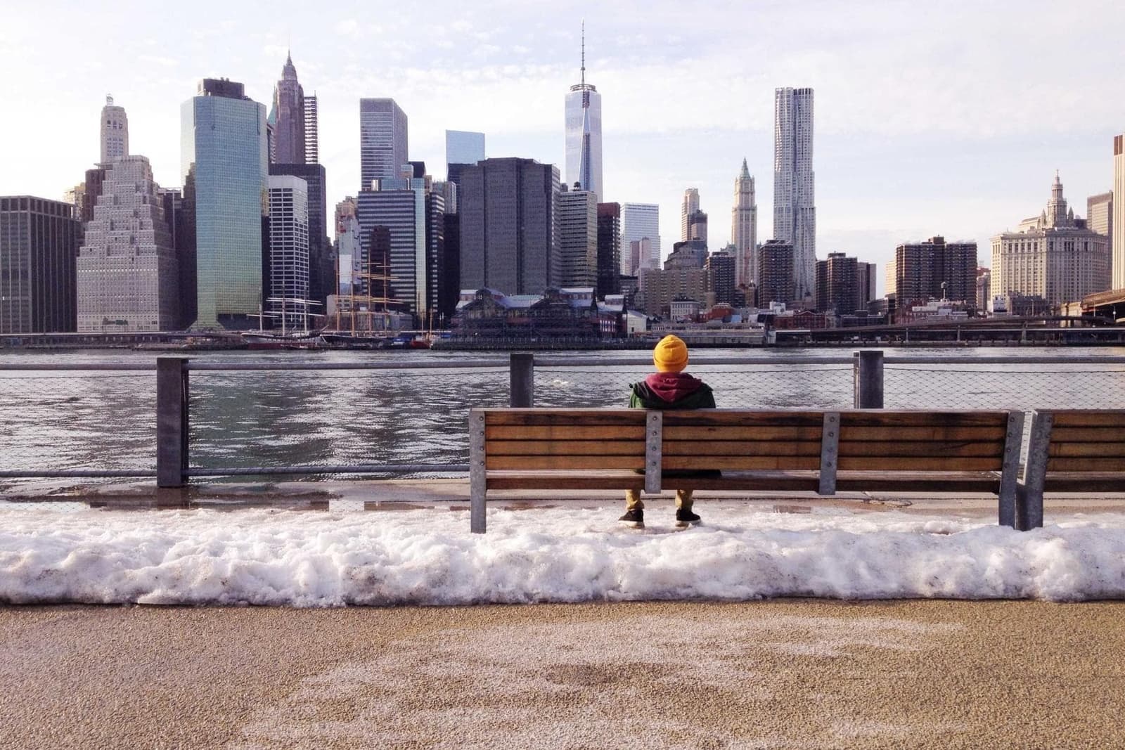 A person on a bench facing a city skyline.